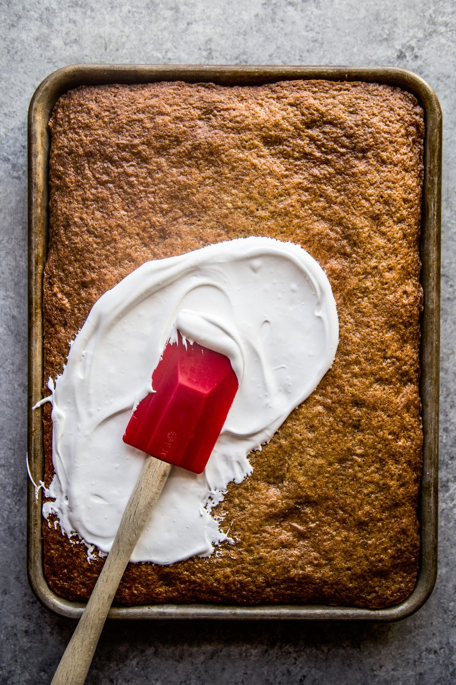 carrot cake being frosted with ginger marshmallow frosting