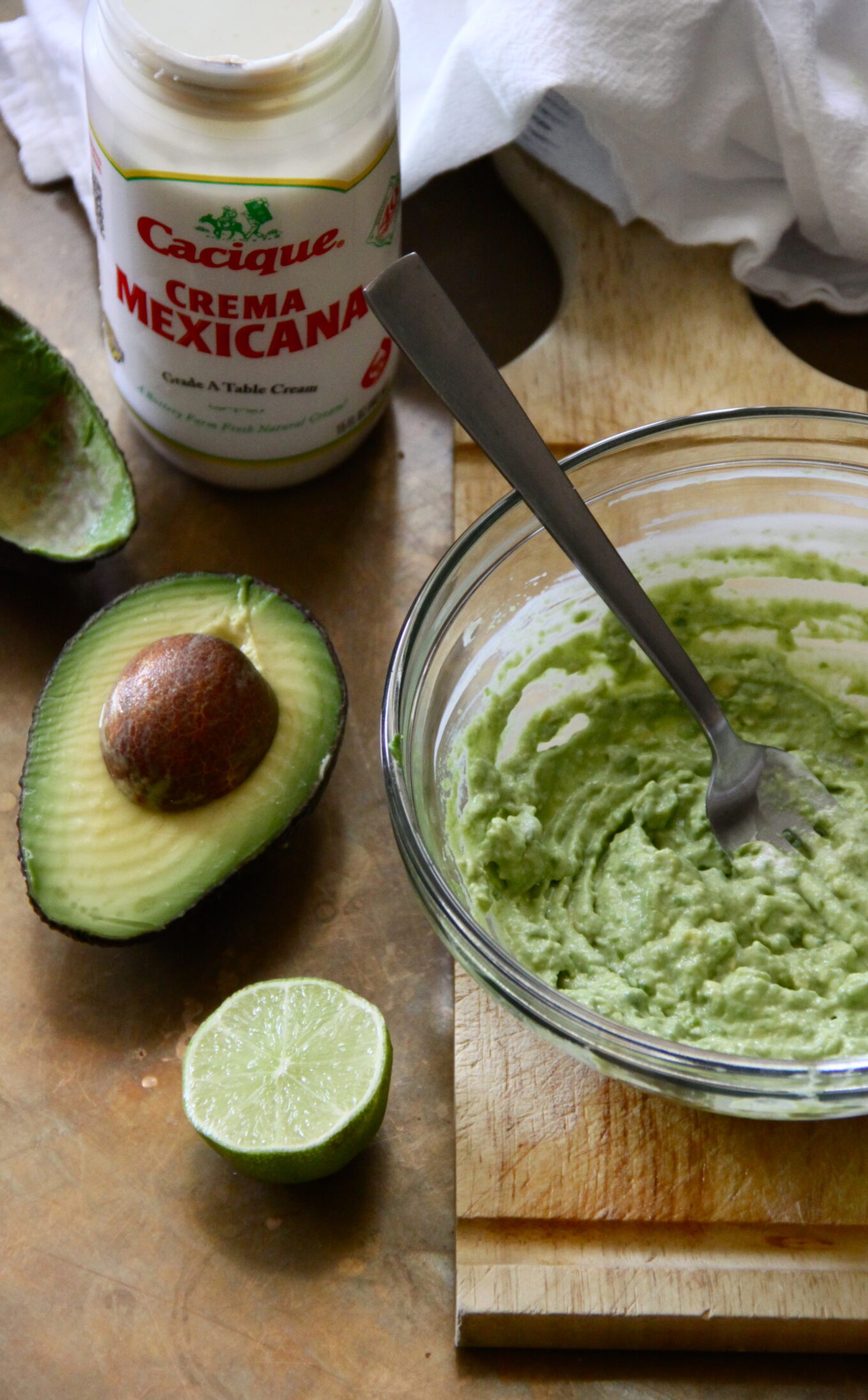 Avocados and crema mixed in a bowl.