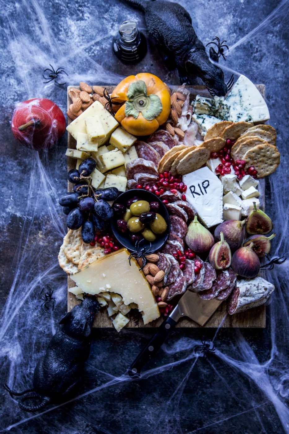 Halloween charcuterie board decorated with cobwebs, spiders, and black rats.