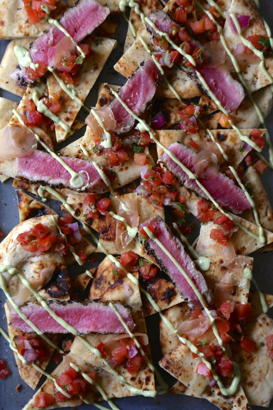 Seared sesame ahi tuna naan nachos, finished with avocado wasabi cream & pickled ginger