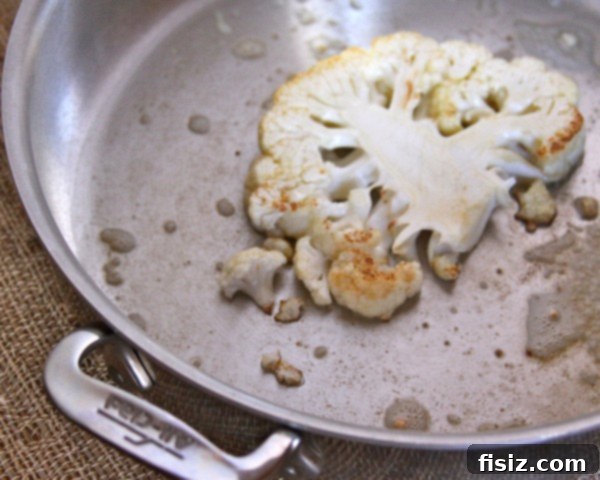 Cauliflower Steak Plating Three pan-roasted cauliflower steaks arranged on a serving plate