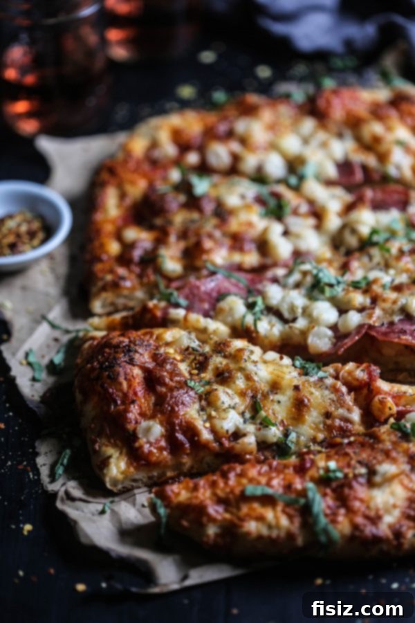 Smoked Mozzarella, Salami and Hominy Pizza 7 Close-up of a slice of Salami, Hominy, and Smoked Mozzarella Pizza on a serving board