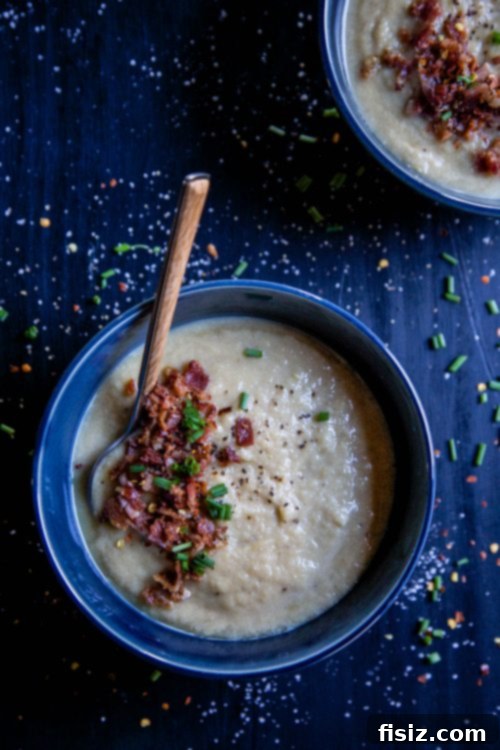 Smoky Bacon Cauliflower Comfort 5 A cozy scene of Cauliflower Bacon Soup in a bowl, with a spoon, ready to be enjoyed, hinting at warmth and comfort.