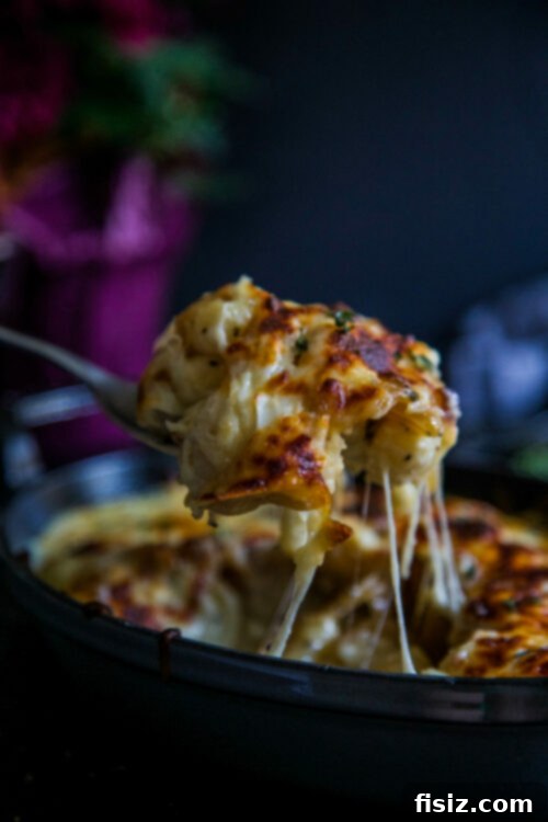 French Onion Gnocchi Gratin 2 A bubbling French Onion Gnocchi Casserole topped with golden-brown melted mozzarella cheese, fresh thyme, and perfectly caramelized onions visible beneath, served in a rustic ceramic baking dish.