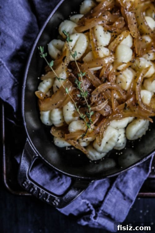 French Onion Gnocchi Gratin 5 A large, family-style French Onion Gnocchi Casserole in a rustic baking dish, fresh out of the oven, with golden-brown cheese and thyme garnish.