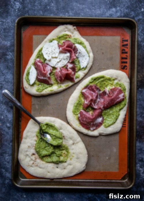 Creamy Avocado Pesto Flatbread with Soppressata and Melted Mozzarella 4 Several Mozzarella and Soppressata Flatbreads with Avocado Pesto arranged on a white serving dish