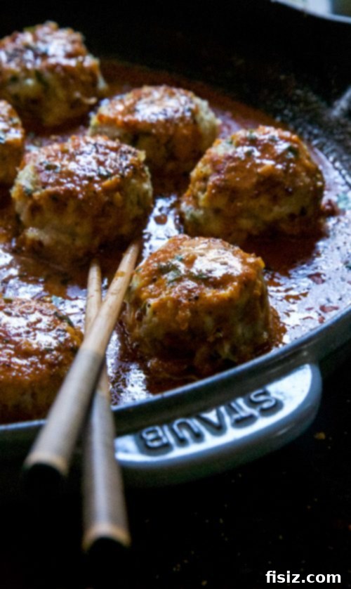 Fragrant Thai Red Curry Chicken Meatballs 5 A bowl of Thai Red Curry Chicken Meatballs served with spiraled zucchini noodles, garnished with fresh cilantro.
