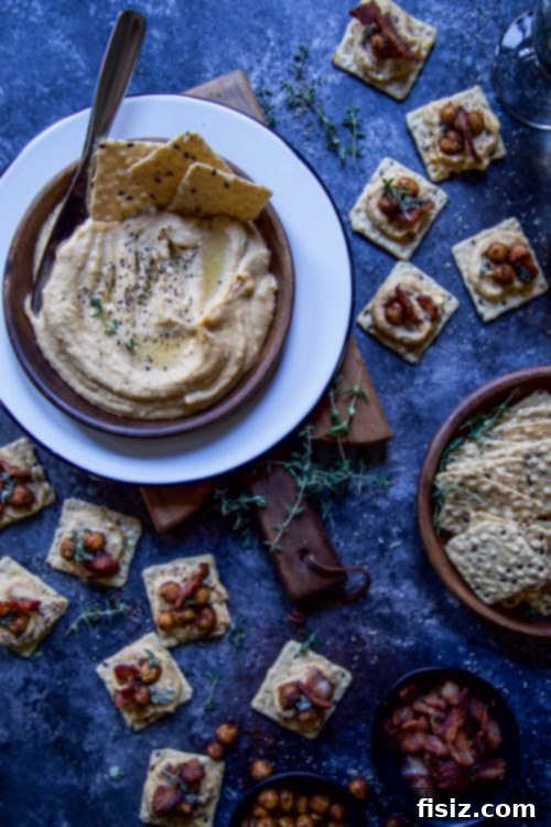 Autumn Pumpkin Hummus with Crispy Spiced Chickpeas and Smoky Sage Bacon 6 An overhead shot of the full Pumpkin Hummus spread, featuring the large bowl of hummus, a variety of Harvest Stone crackers, and a wooden serving spoon, ready for a party.