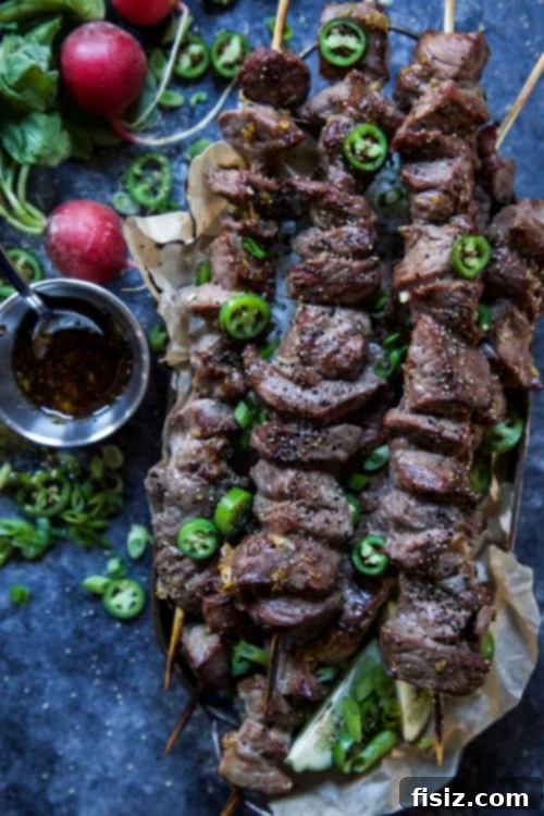 Lemongrass Vietnamese Beef Skewers 5 Platter of grilled Spiced Vietnamese-Style Beef Skewers garnished with fresh lime and herbs.