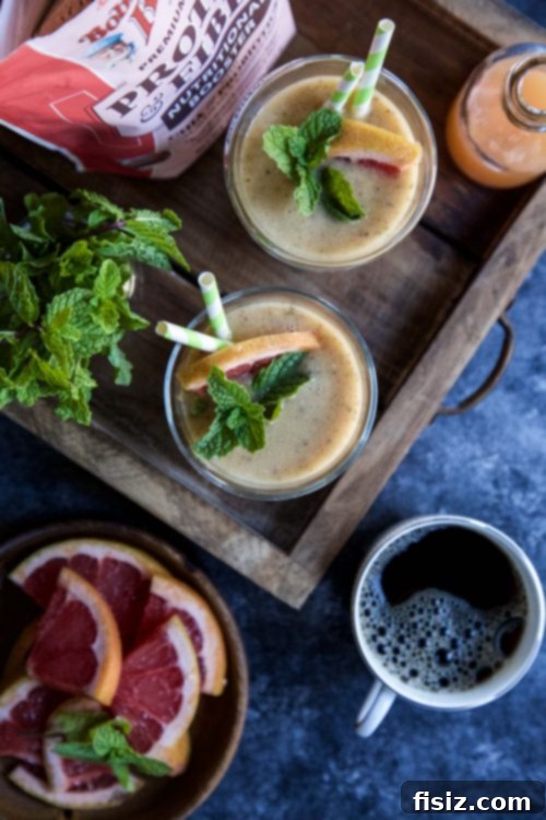 Zesty Citrus Ginger Smoothie 5 Ingredients for Grapefruit-Ginger Burst Smoothie, including grapefruit, ginger, peaches, Bob's Red Mill Protein + Fiber Booster, and mint, laid out on a wooden surface.