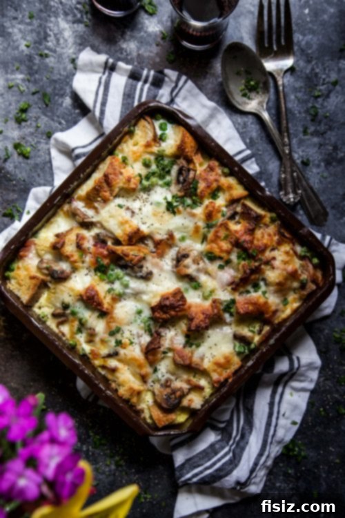 Golden-brown Bacon, Burrata & Smoked Mozzarella Strata baking in a dish, ready to be served for brunch. The top is bubbly and slightly browned.