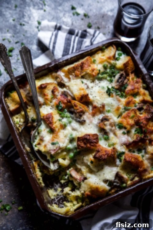 Prepared Bacon, Burrata & Smoked Mozzarella Strata in a white ceramic baking dish, ready for the oven with its rich, savory ingredients visible.