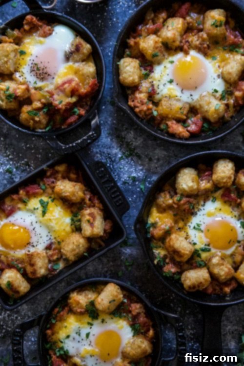 Crispy Tot Shakshuka 5 Individual serving of Tot Shakshuka, with eggs nestled in the spicy tomato sauce and tater tots scattered on top, ready to eat.