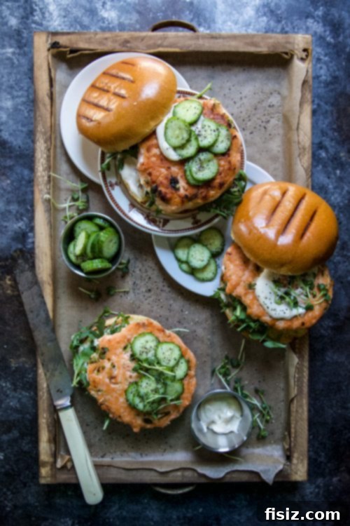 Easy Ginger Salmon Burgers and Crisp Pickled Cucumbers 6 Assembled Ginger Salmon Burgers with Pickled Cucumbers on a wooden board