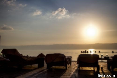 Dead Sea Jordan Accommodations Dining and Attractions 11 Guests enjoying a drink by an infinity pool with the Dead Sea sunset in the background