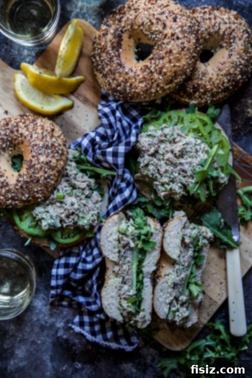 Everything Bagel Green Goddess Tuna Salad 7 Two halves of an Everything Bagel loaded with Green Goddess Tuna Salad, garnished with fresh arugula and tomato