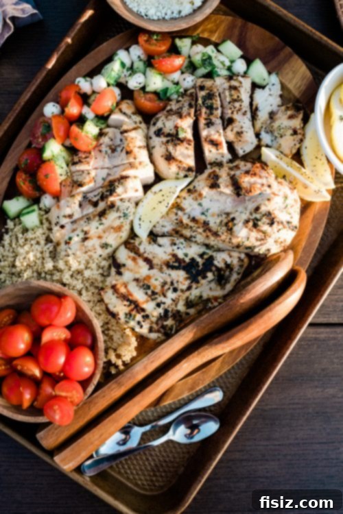 Tahini Grilled Chicken with Fresh Cucumber Caprese 3 Close-up of a hand placing a tahini marinated chicken breast on a hot grill for summer cooking.