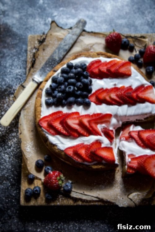 Stars & Stripes Cookie Cake with Fluffy Marshmallow Topping 6 A slice of American Flag Cookie Cake being served, showing the layers of cookie, frosting, and berries.