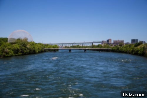 Spectators walking across a bridge towards the Circuit Gilles Villeneuve, with water visible below.