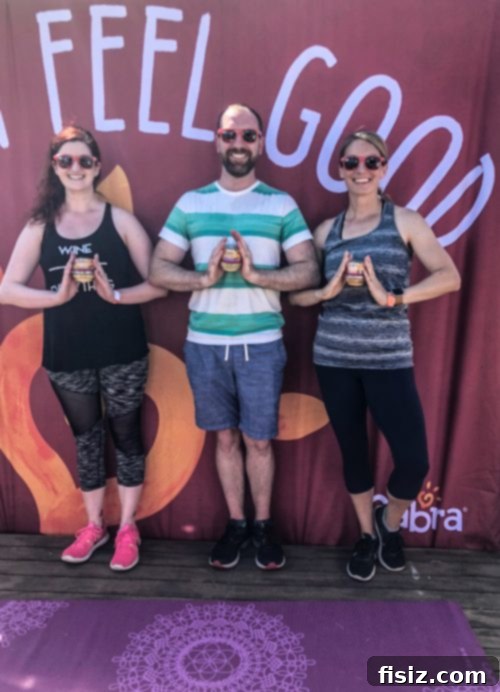 A group of friends smiling and posing with a yoga wheel and Sabra snacks.