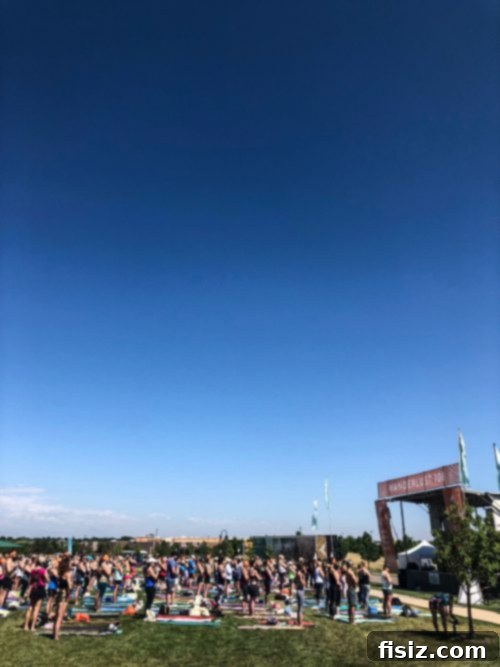 A massive crowd participating in an outdoor yoga session on a grassy field.