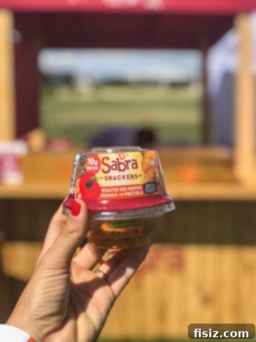A person posing happily with a Sabra Snacker in hand, showcasing the delicious snack.