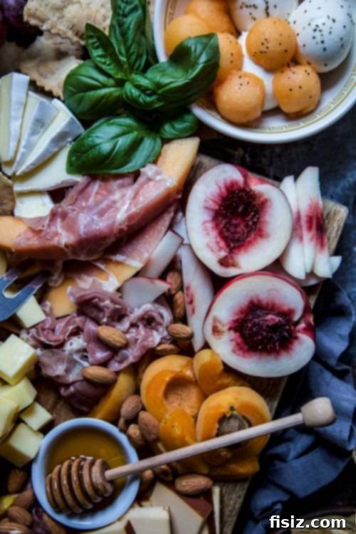 A close-up of a charcuterie board, highlighting the juicy stone fruits and various cheeses.
