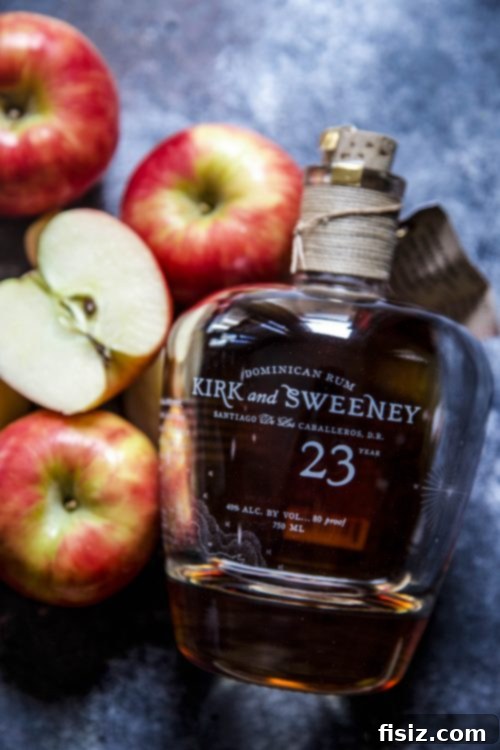 Harvest Apple Rum Cooler 4 A vibrant Apple Cider Rum Cooler cocktail, garnished with a crisp apple slice and fresh mint leaves, set against a blurred background, inviting a refreshing sip.