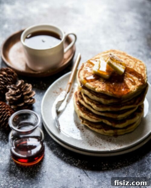 Golden Tahini Chai Pancakes 2 Fluffy Tahini Chai Pancakes drizzled with maple syrup on a plate, ready to be enjoyed.