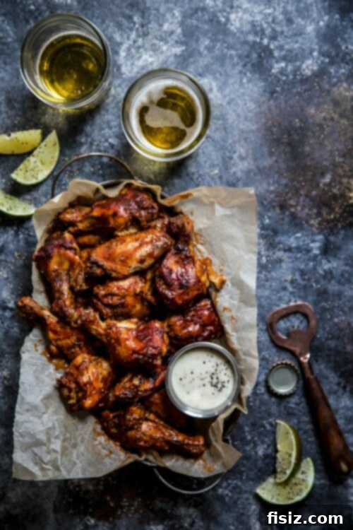 Tender Slow Cooker Chipotle Bourbon Chicken Wings 5 A serving platter filled with slow-cooked chicken wings, garnished with fresh herbs and lime wedges, ready for a gathering.