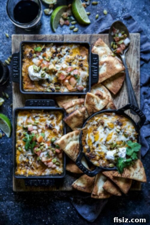 Creamy Golden Pumpkin & Butternut Queso 2 A large bowl of creamy roasted butternut squash and pumpkin queso dip, garnished with fresh cilantro and pepitas, served with tortilla chips on a rustic wooden board.