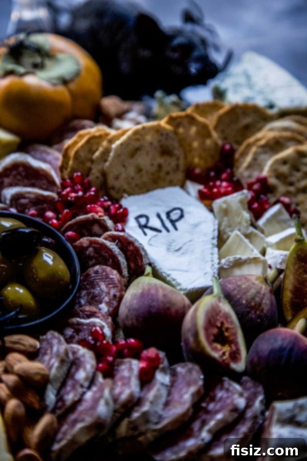 Crafting a Killer Halloween Charcuterie Board 3 Close-up of a wheel of brie cheese artfully shaped into a coffin, with "RIP" meticulously written on its surface using a black food coloring marker, contributing to the spooky Halloween theme.