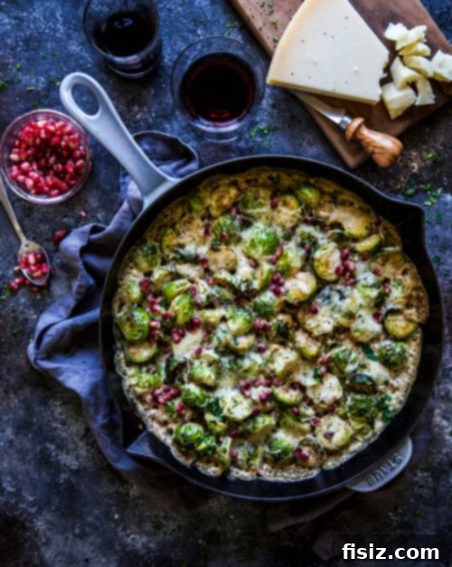 Colorful close-up of pomegranate arils on top of a cheesy Brussels sprout bake.
