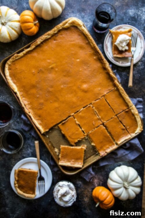 golden brown sheet pan pumpkin pie cut into neat bars, garnished with whipped cream and a sprinkle of cinnamon