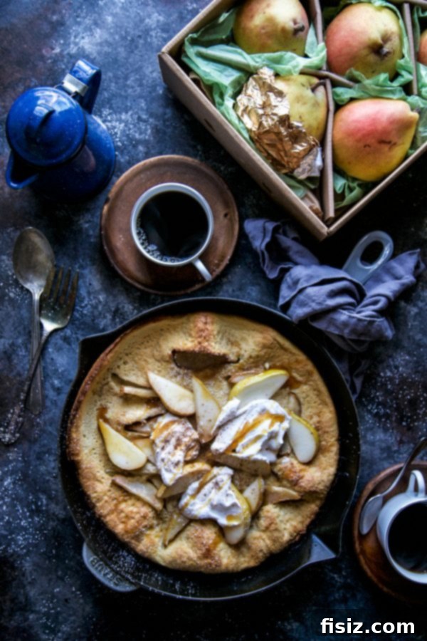 Autumn Pear Dutch Baby 2 A beautifully golden-brown Puffed Pear Pancake, garnished with fresh pear slices, whipped cream, and maple syrup, ready to be served for a festive breakfast or dessert.