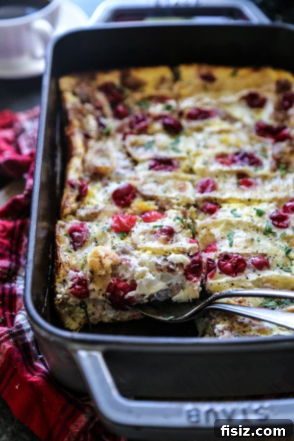Sausage Cranberry and Brie Breakfast Strata 5 A partially assembled Sausage, Cranberry, and Brie Egg Casserole, layered with ingredients in a baking dish.
