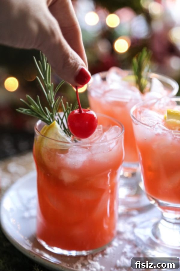 A close-up of Christmas Morning Punch being poured into a glass filled with ice, showing its vibrant red color.