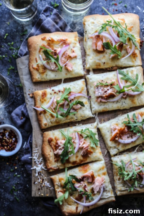 Close-up of Smoked Salmon White Pizza, showing golden crust, creamy white sauce, smoked salmon pieces, and fresh arugula