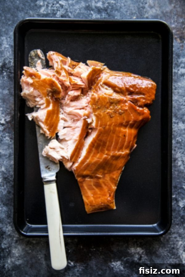 A slice of Smoked Salmon White Pizza being lifted, showing the melted cheese and flaky salmon
