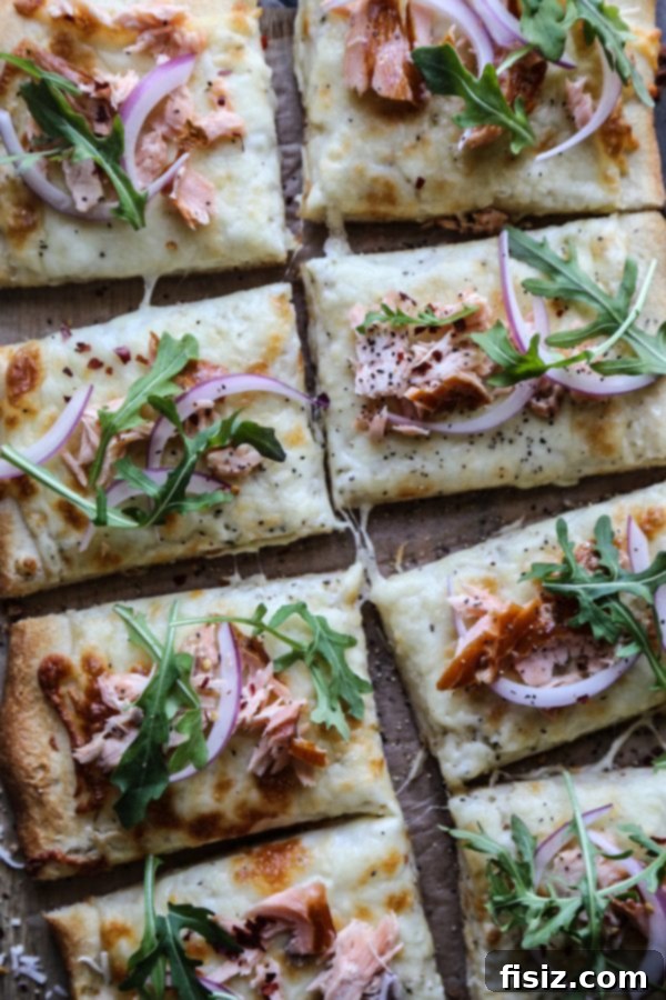 Freshly baked Smoked Salmon White Pizza, garnished with arugula and red onion