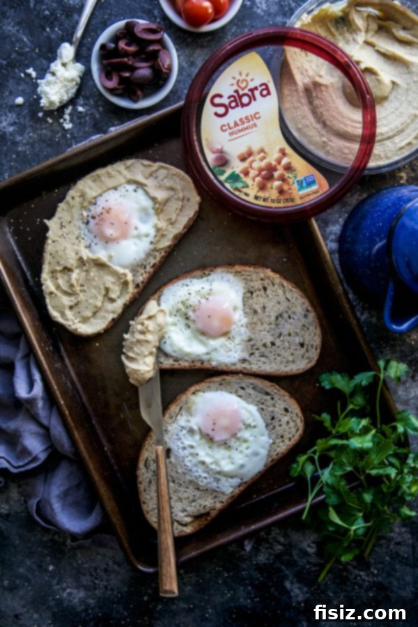 Mediterranean Egg Nest Toast with Hummus 4 Assortment of fresh ingredients for Mediterranean Egg-in-a-Hole Toast, including bread, eggs, hummus, and vegetables
