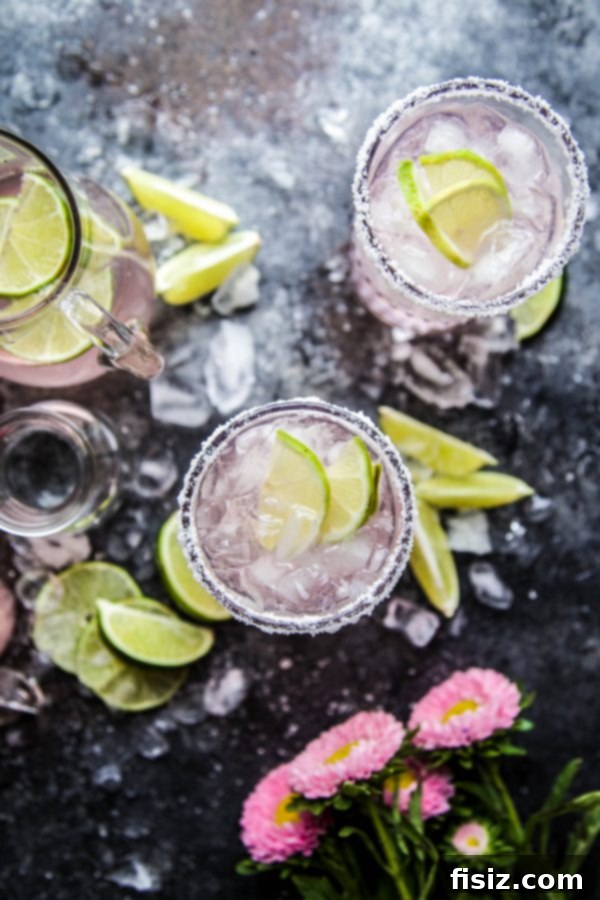 Blushing Citrus Margarita 3 Close-up of a Pink Lime Margarita glass with a salted rim and lime garnish, highlighting its refreshing appeal.