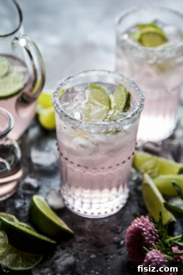 Blushing Citrus Margarita 6 A hand holding a Pink Lime Margarita against a bright background, emphasizing its refreshing qualities.