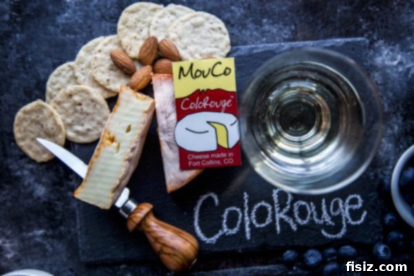 MouCo Cheese And Wine Pairing 4 A close-up of a slice of MouCo ColoRouge cheese, showcasing its reddish-orange rind and creamy interior, ready to be paired with wine.