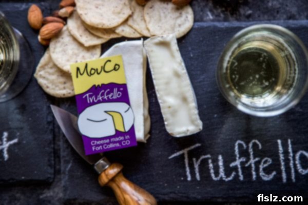 MouCo Cheese And Wine Pairing 7 A wedge of MouCo Truffello cheese, showing its creamy interior speckled with black truffles, paired with a flute of sparkling Prosecco.