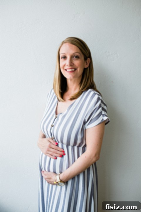 My Bump Update Weeks 23-27 3 Pregnant woman in a flowing maternity dress, gently holding her baby bump against a natural backdrop.