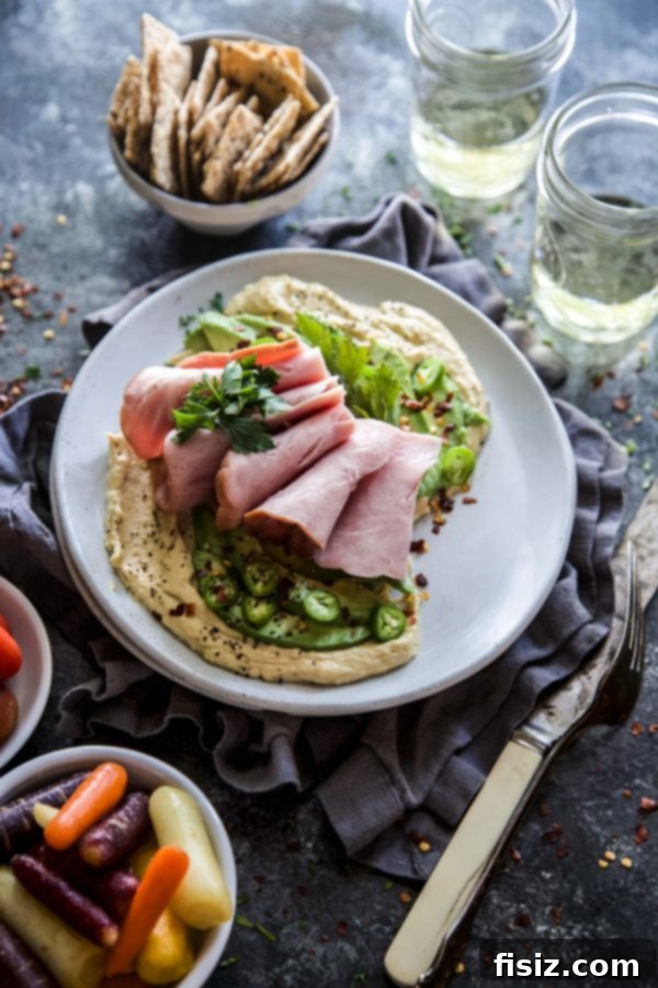 Spiced Avocado and Ham Loaded Hummus 5 Platter of Hummus with Spiced Avocado & Ham served with crackers and vegetables.