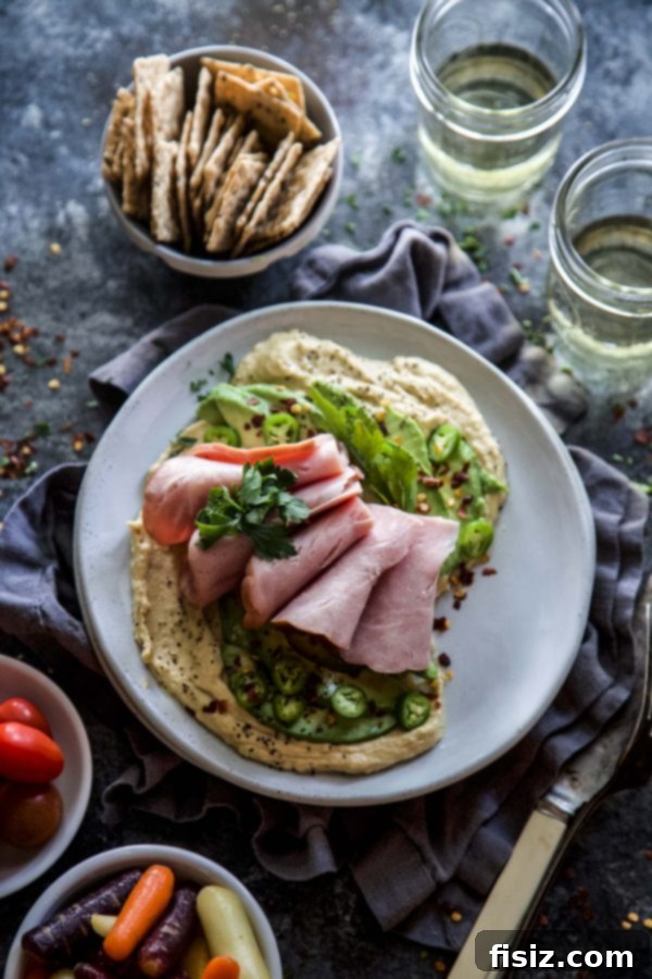 Spiced Avocado and Ham Loaded Hummus 6 Overhead shot of Hummus with Spiced Avocado & Ham spread on a plate with garnishes.