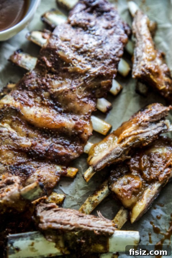 Bourbon Glazed American Lamb Ribs 6 A hand holding a perfectly cooked BBQ Bourbon Grilled American Lamb Rib