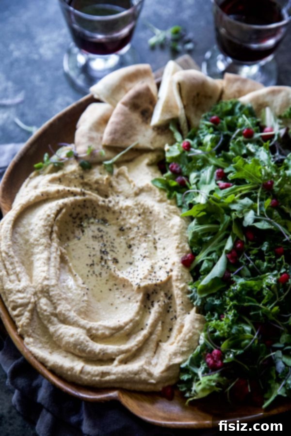 Golden Sweet Potato Hummus with Fresh Harvest Greens 5 A festive serving of Sweet Potato Hummus with Harvest Greens, garnished with pomegranate and pita